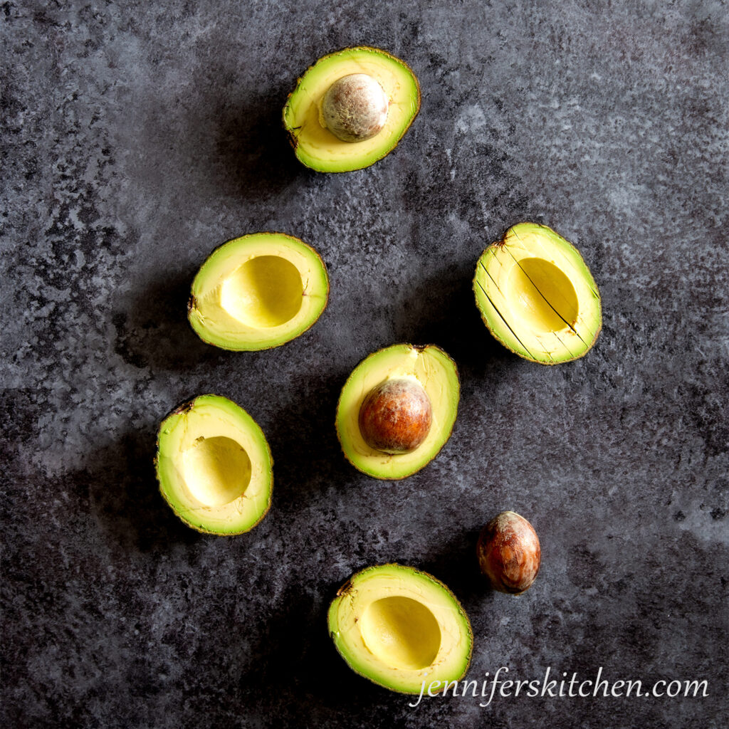 Cut avocado halves on dark background