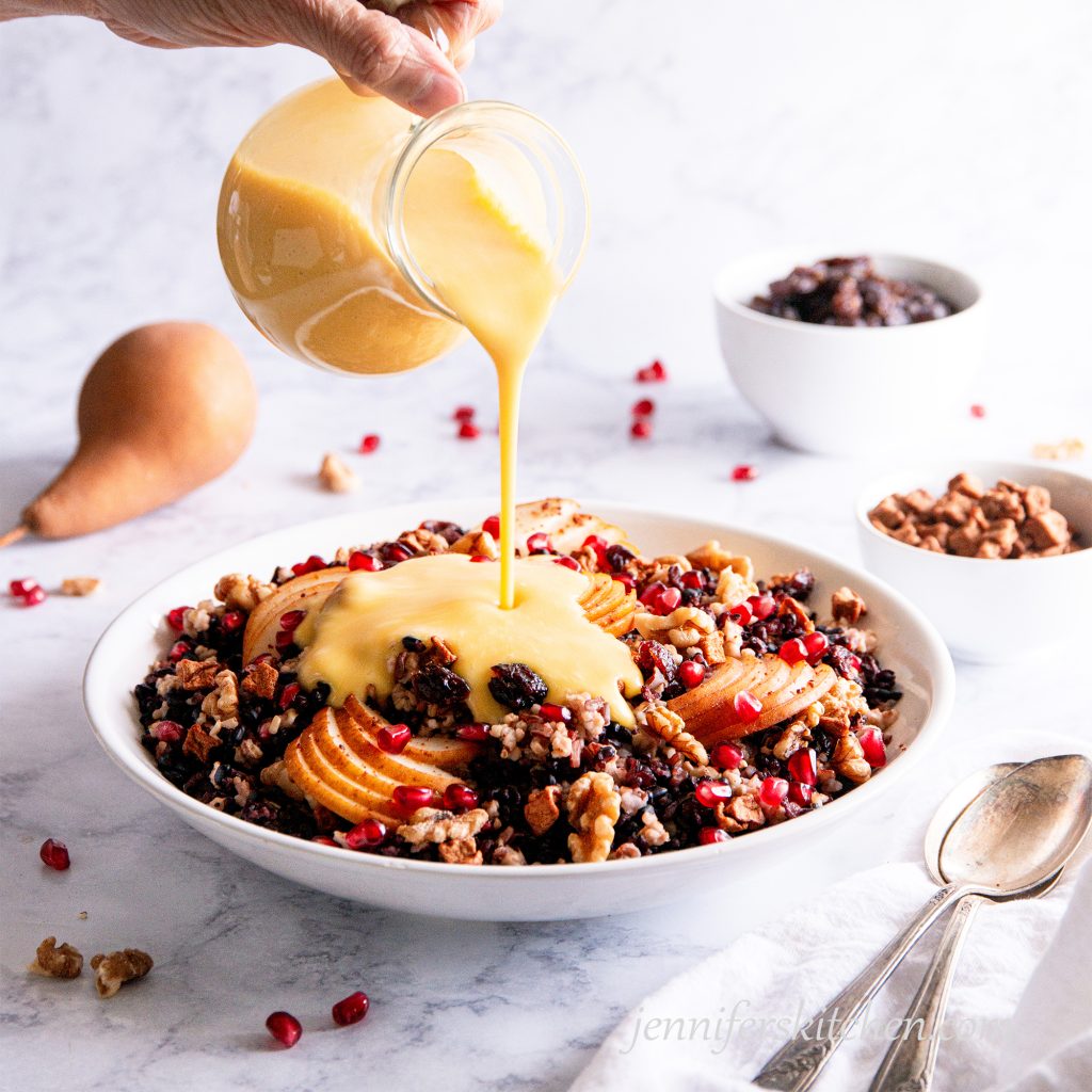 Pouring a creamy sauce over Gluten-Free Breakfast Grain Salad