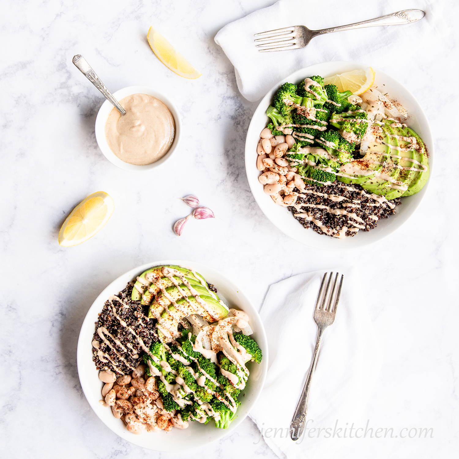 Two Broccoli Bowls with Tahini Sauce and fresh lemon on the side