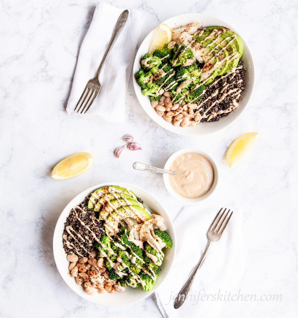 Two Broccoli Bowls with Tahini Sauce and fresh lemon on the side