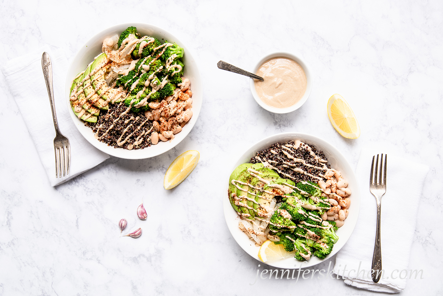 Two Broccoli Bowls with Tahini Sauce and fresh lemon on the side