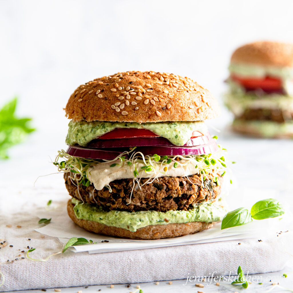 Walnut Pesto Burger Sandwich with sprouts, vegan mayo, red onion, tomato, and pesto.