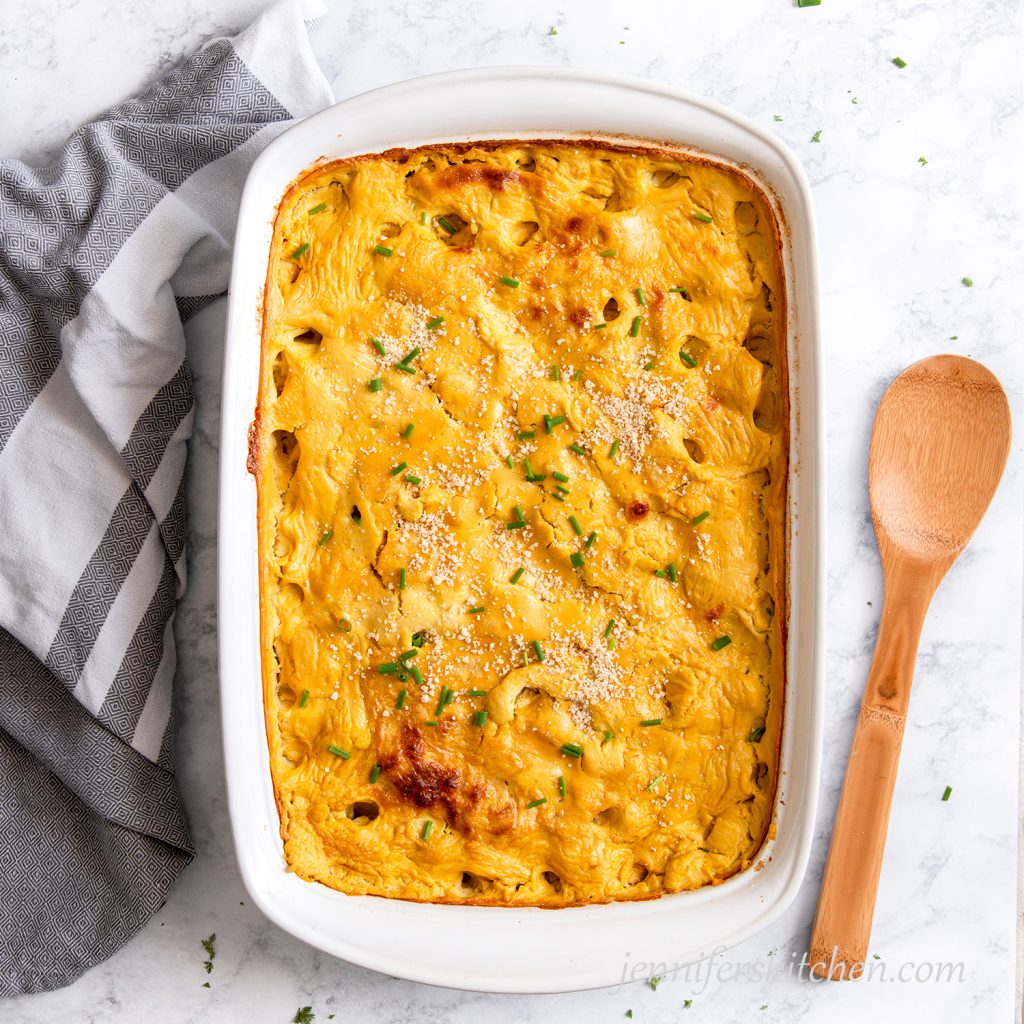 Cheesy Potato Casserole in a white dish topped with fresh chives and vegan parmesan.