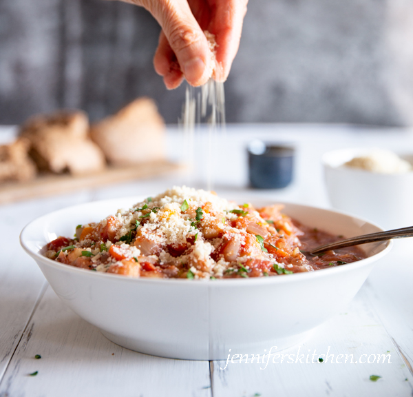 sprinkling vegan parmesan onto a yummy chickpea dish