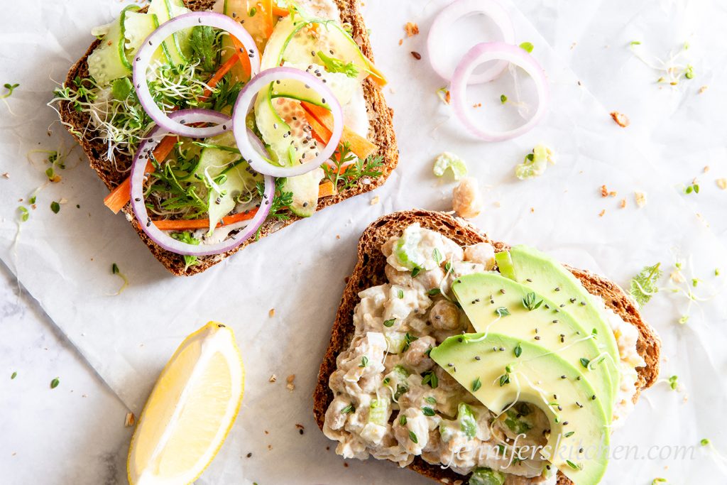 Open-face No-Mayo Vegan Chickpea Salad Sandwich topped with avocado, cucumber, sprouts, and onions.