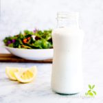 Vegan, Vinegar-Free Creamy Cashew Salad Dressing in a jar with a salad in the background