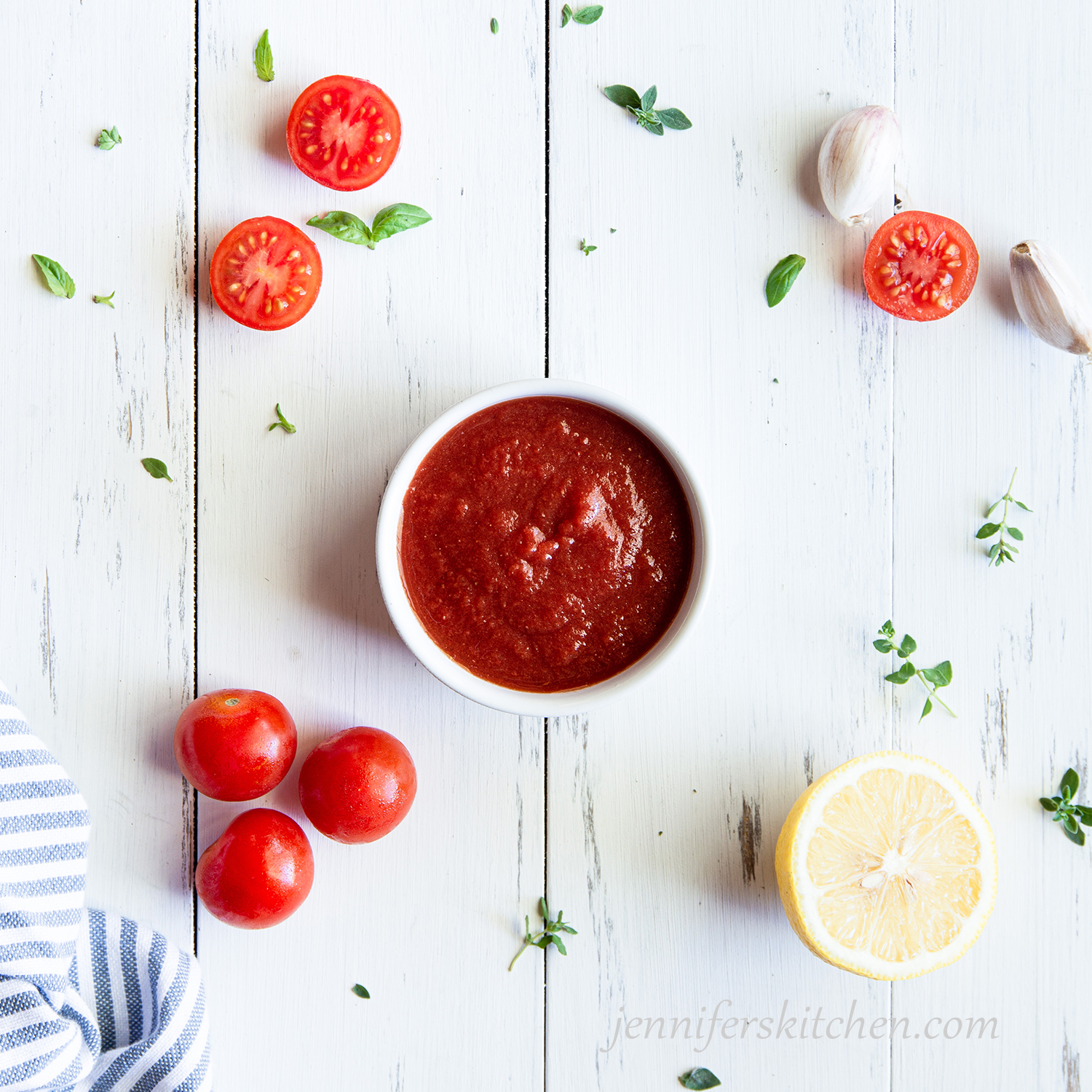 Homemade, vinegar-free ketchup in a bowl with fresh tomatoes and garlic.