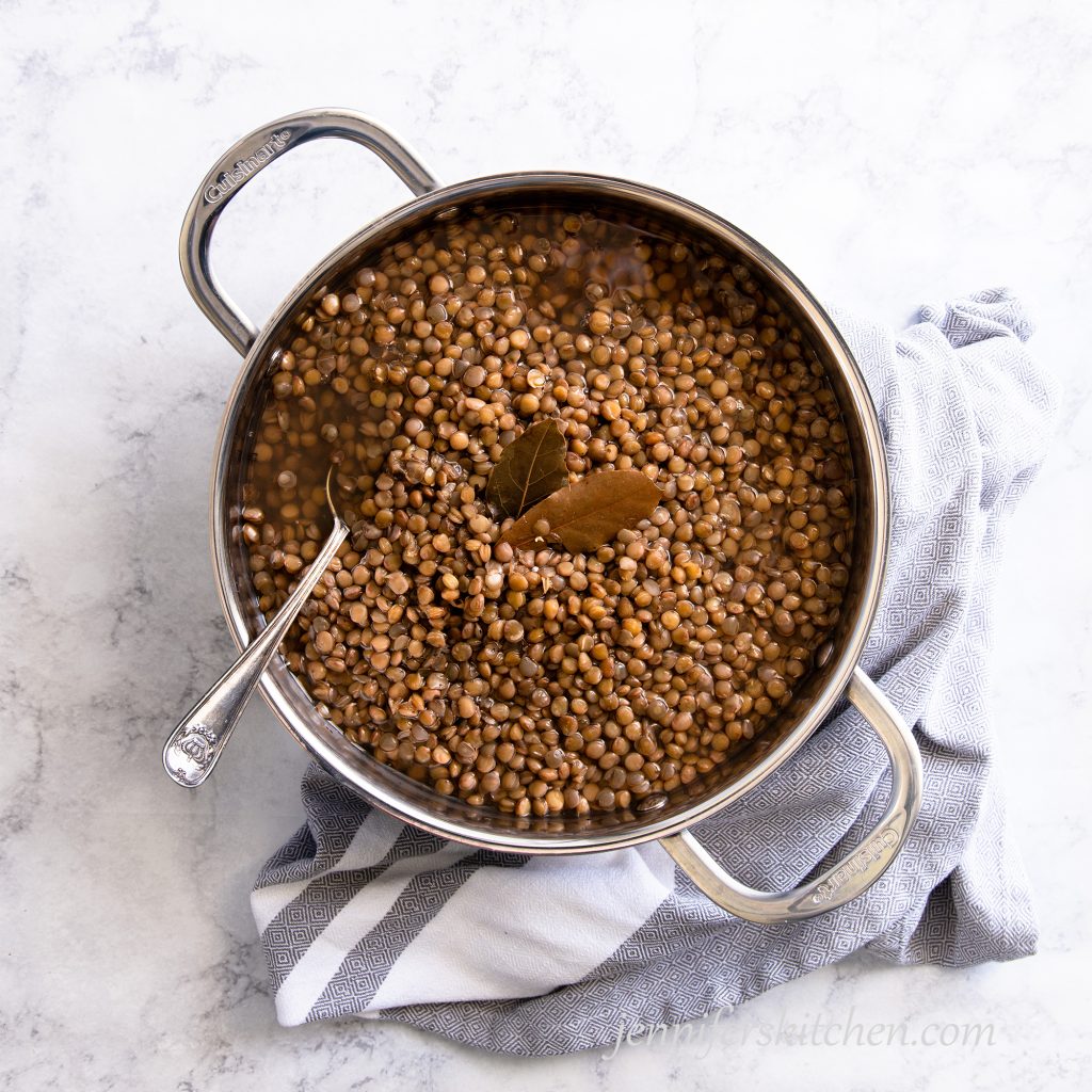 Cooked lentils in a pan with bay leaves