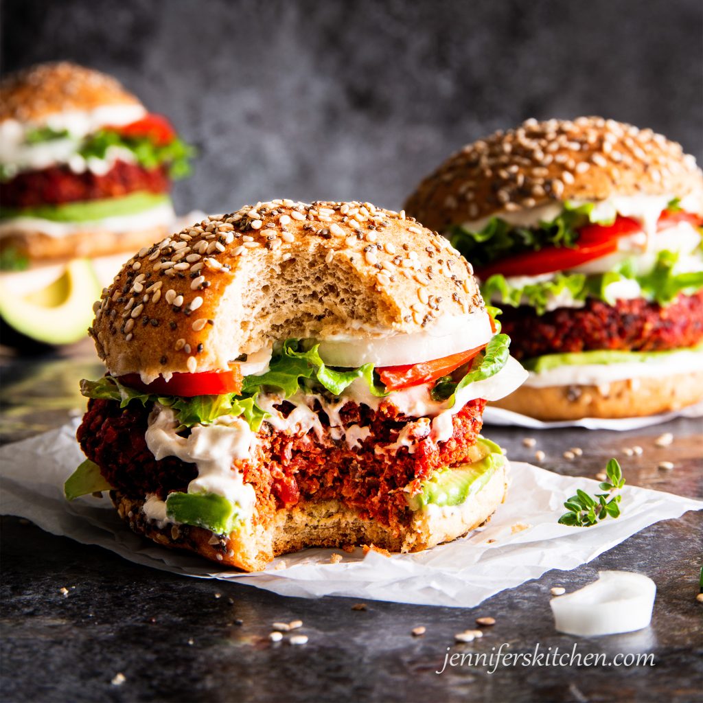 Gluten-free, oil-free beet burger on a bun with toppings with a delicious bite taken out.