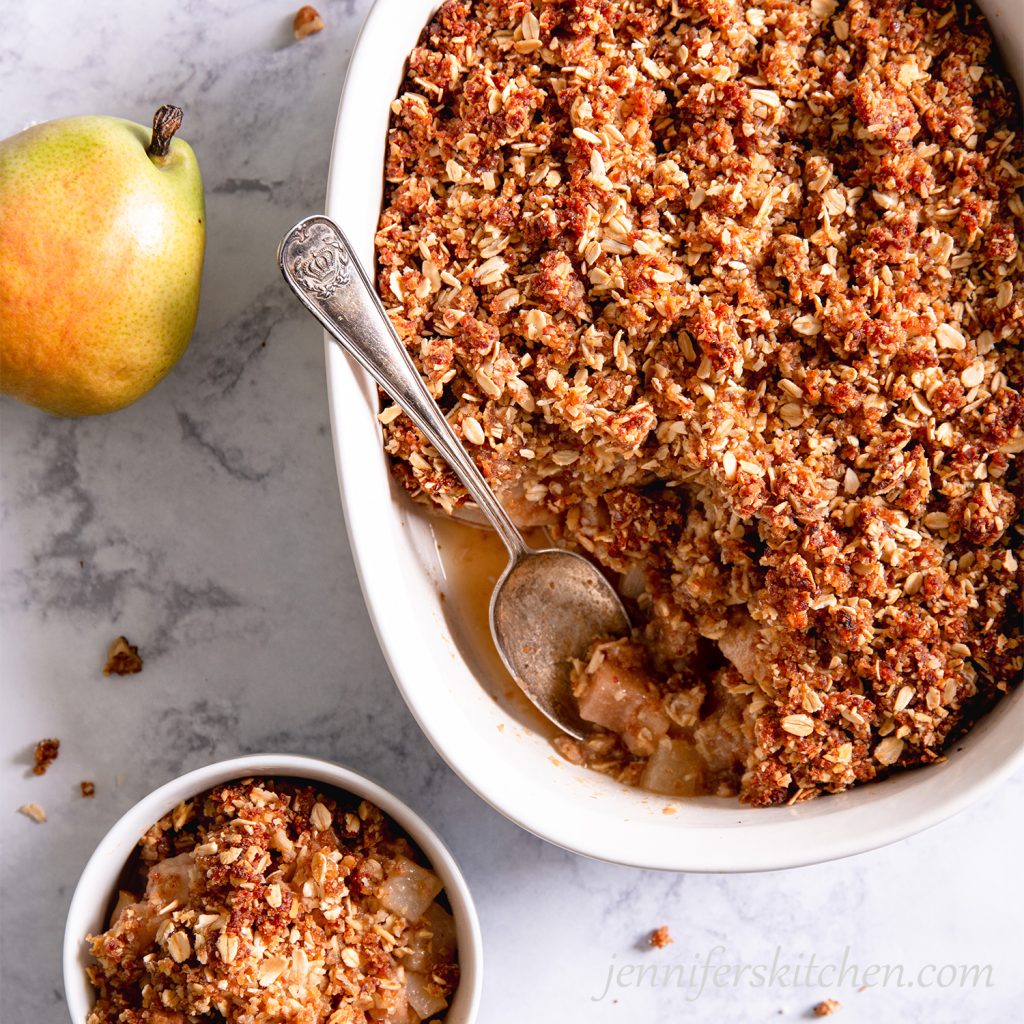 Sugar-Free, Oil-Free, Gluten-Free Pear Crisp in a white casserole dish with a spoon and bowl on the side.