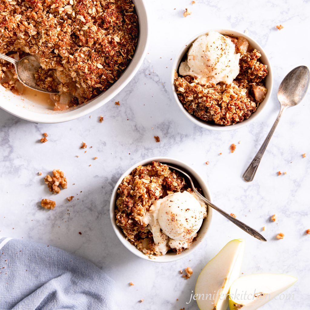 Sugar-Free, Oil-Free, Gluten-Free Pear Crisp in two white bowls topped with sugar-free ice cream.