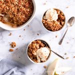 Sugar-Free, Oil-Free, Gluten-Free Pear Crisp in two white bowls topped with sugar-free ice cream.