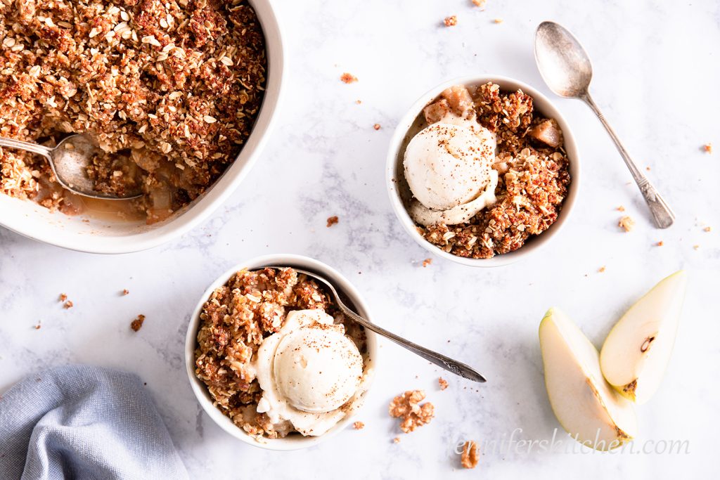 Sugar-Free, Oil-Free, Gluten-Free Pear Crisp in two white bowls topped with sugar-free ice cream.