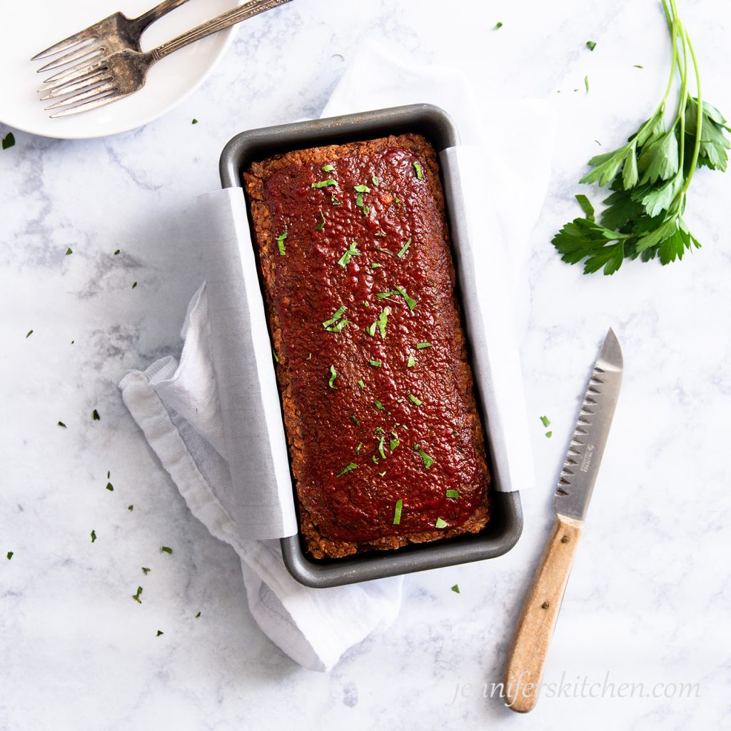 Gluten-free Quinoa Lentil No-Meatloaf in a loaf pan with a knife beside.