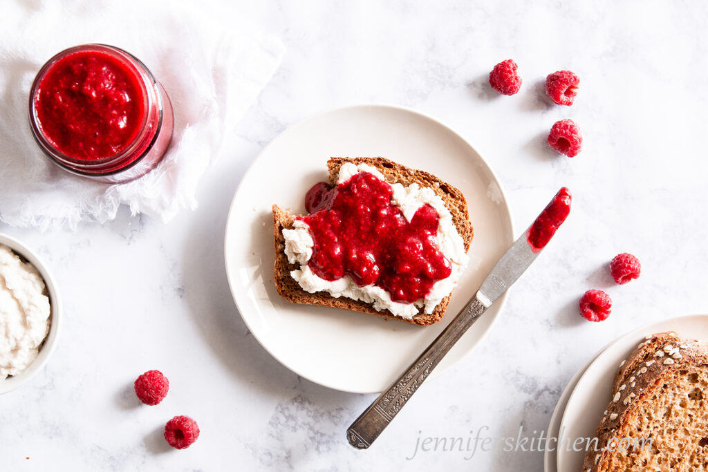 Sugar-Free Raspberry Jam on toast with almond cheese with a bite taken out.