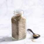 Nutritional yeast free chicky seasoning in a jar with a spoon beside.