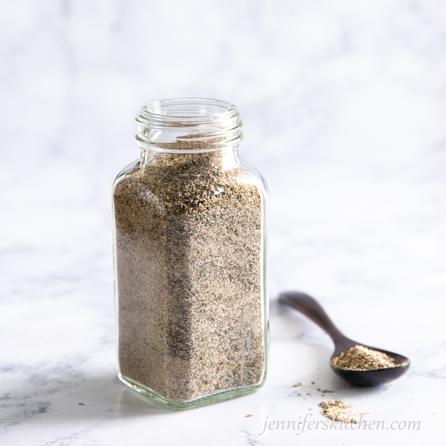 Nutritional yeast free chicky seasoning in a jar with a spoon beside.