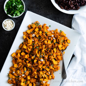 Oil-Free Roasted Sweet Potatoes with cilantro and vegan feta on a serving platter.